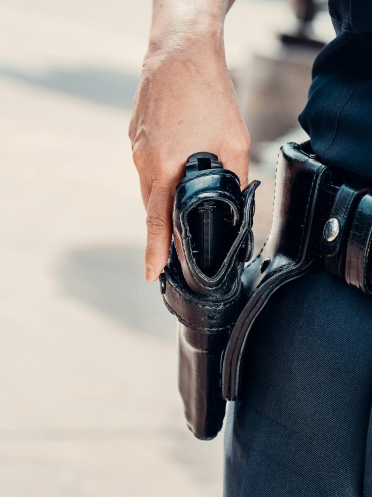 Close-up of a police officer's hand resting on a handgun holster, symbolizing public safety.